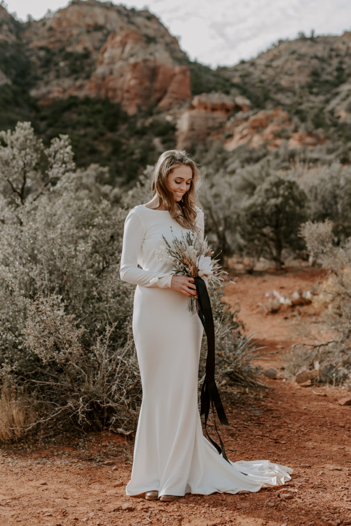 Bride holds her bouquet while posing in the desert during her adventure elopement by Off Path Photography