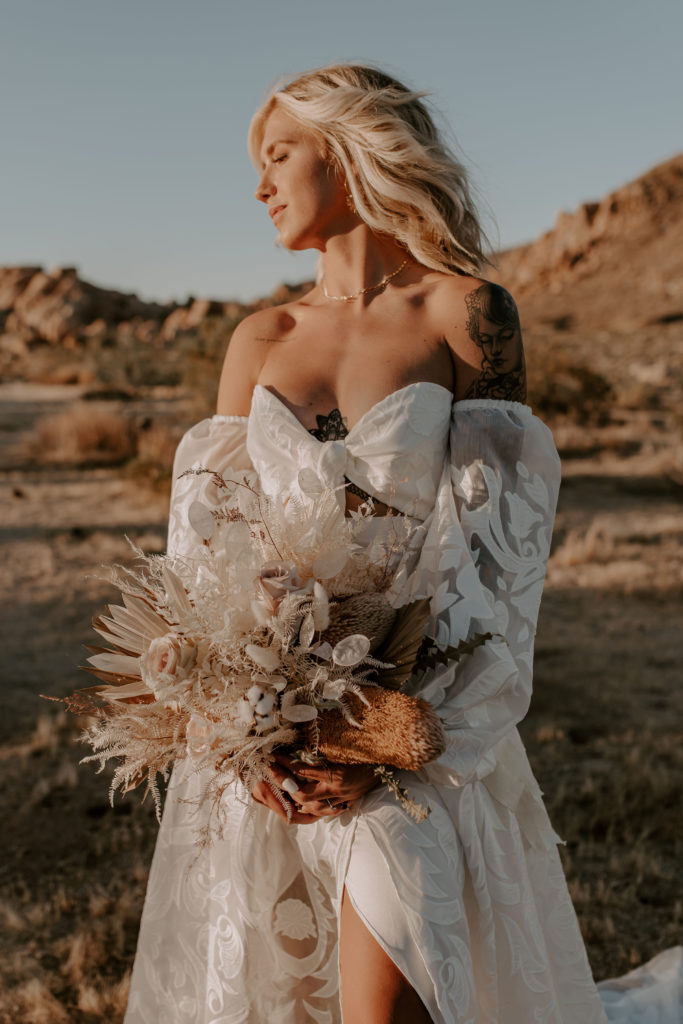 Bride posing in her bridal dress and bouquet during golden hour at Joshua Tree National Park, taken by Off Path Photography