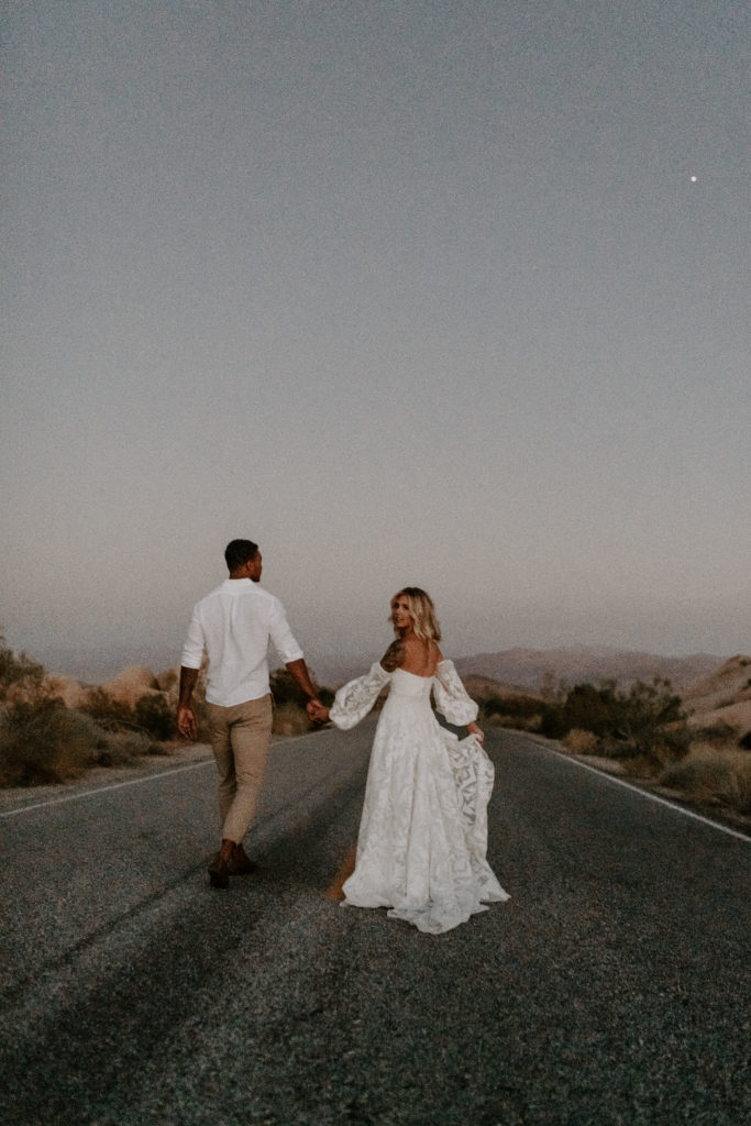 Bride and groom walking hand-in-hand across the highway during their elopement shoot with Off Path Photography