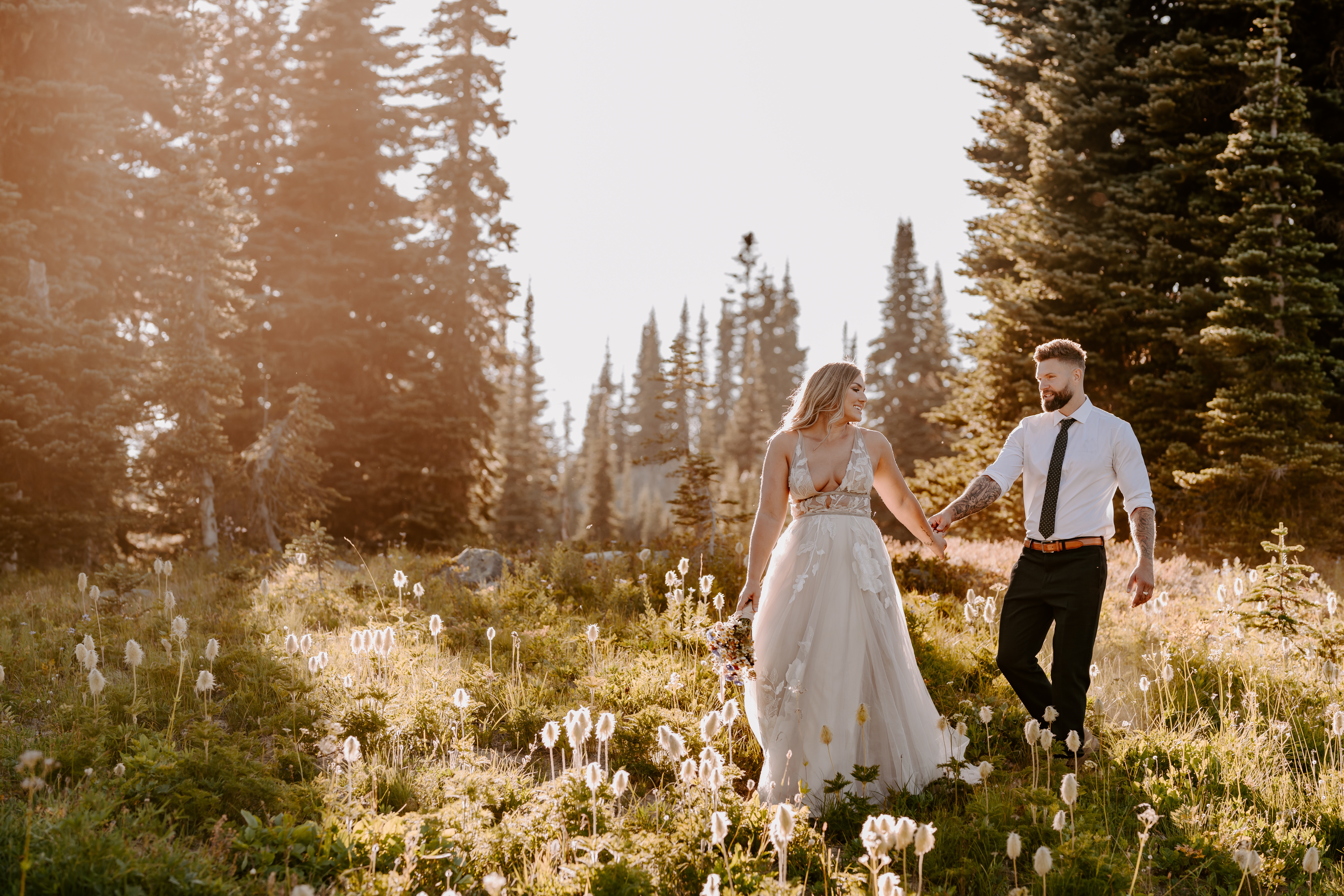 Couple holding hands and smiling as they walk down a clearing in the forest during their Washington State elopement shoot