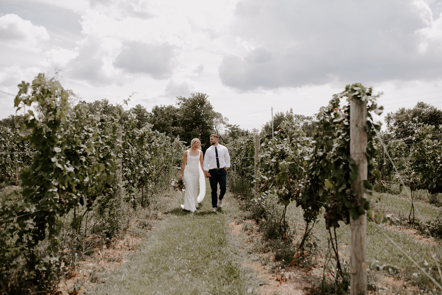 Couple holding hands while walking in a vineyard in Napa County