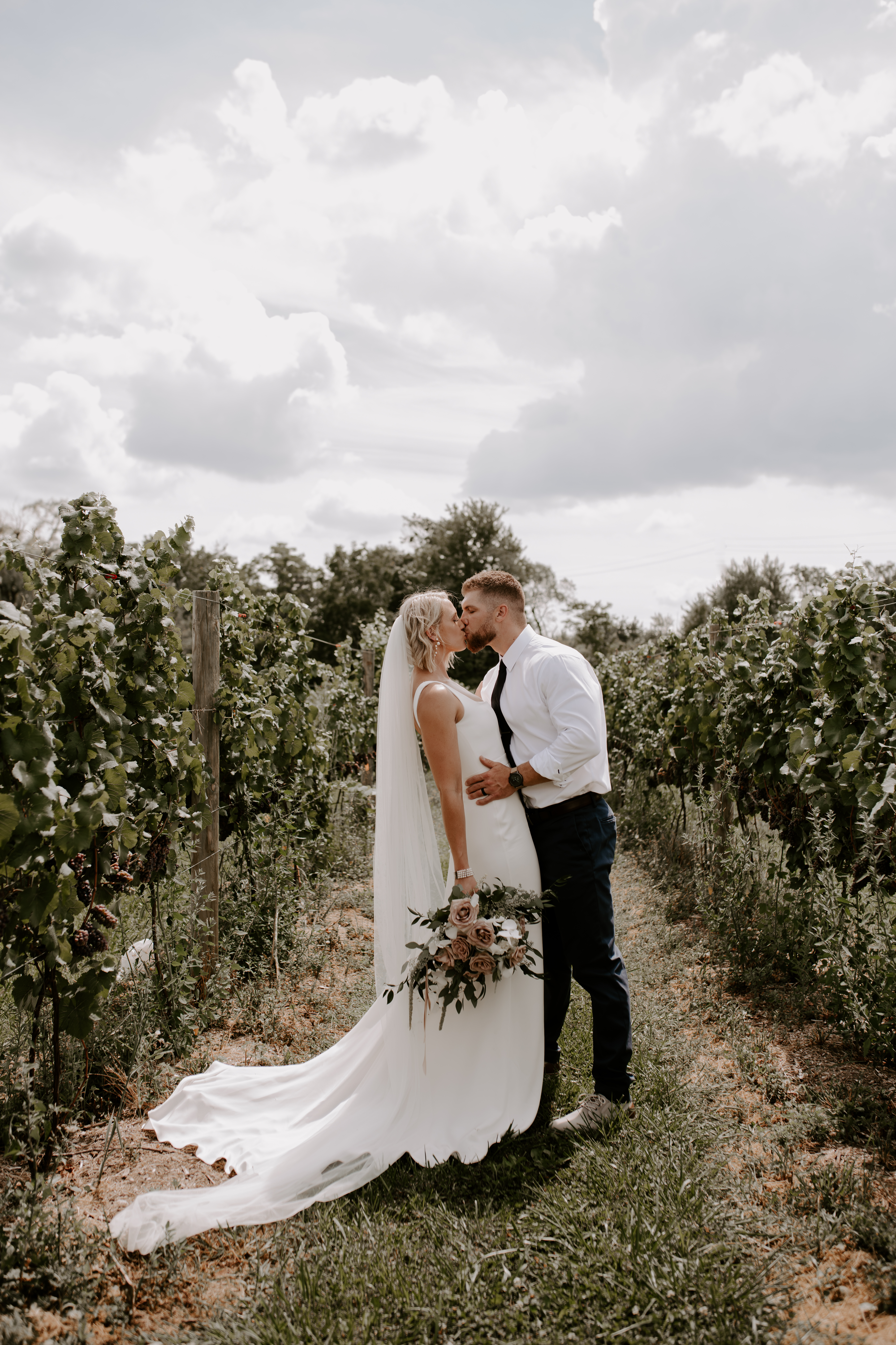 Bride and groom sharing a kiss in the middle of a vineyard, shot by Off Path Photography